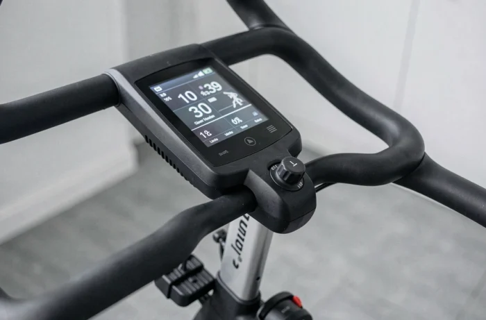 Gros plan sur le tableau de bord et les commandes d'un vélo d'appartement connecté avec affichage digital
